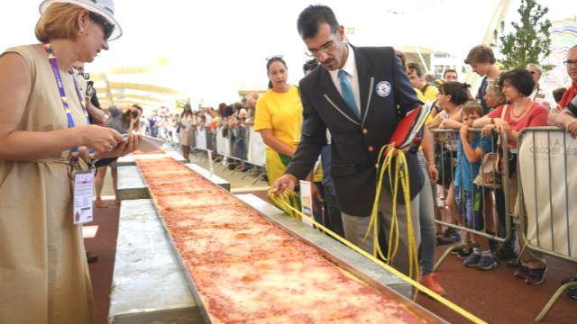 LONGEST PIZZA. Italy's judge of the Guinness World Record Lorenzo Veltri  measures the length of the Pizza to be the longest in the world with 1600m long, on June 20 in Milan at the Expo Milano 2015. Photo by Olivier Morin/AFP  
