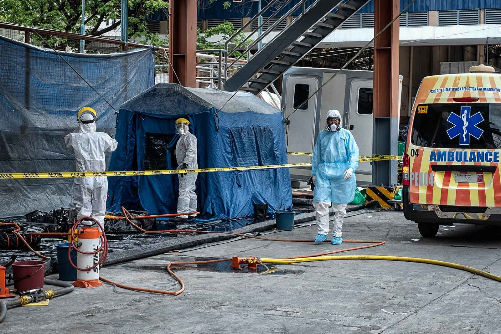 FULL GEAR. The Pasig Disaster Risk Reduction and Management Office decontaminates its ambulance personnel who helped transport a suspected COVID-19 case on March 15, 2020. Photo by Joser Dumbrigue/Rappler  