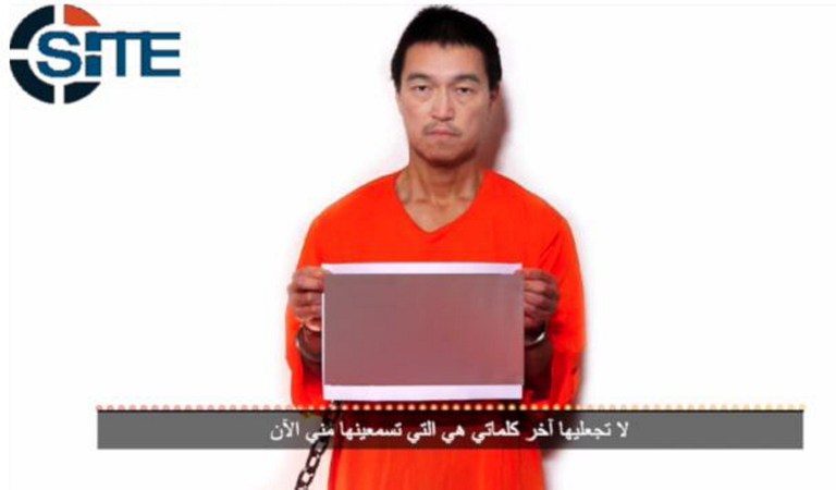 This image obtained from the SITE Intelligence Group on January 24, 2015, shows a still image of Japanese hostage Kenji Goto holding a photograph allegedly showing Haruna Yukawa's slain body, with an audio recording in which Goto spoke of the Islamic State (ISIS) group demand for a prisoner exchange to guarantee his release. The image held by Goto was blocked and not displayed in the video shown by the SITE Intelligence Group.  SITE Intelligence Group/Handout/AFP