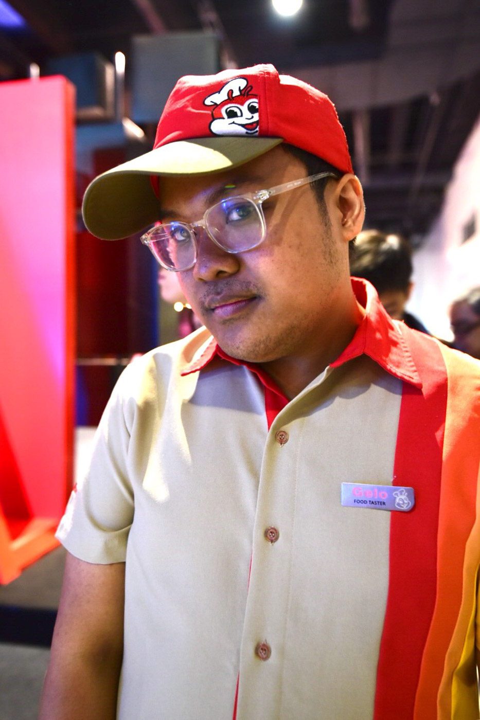 FOOD TASTER. A Jollibee hat, shirt, and a pin that says 'Food Taster' is part of his costume. 