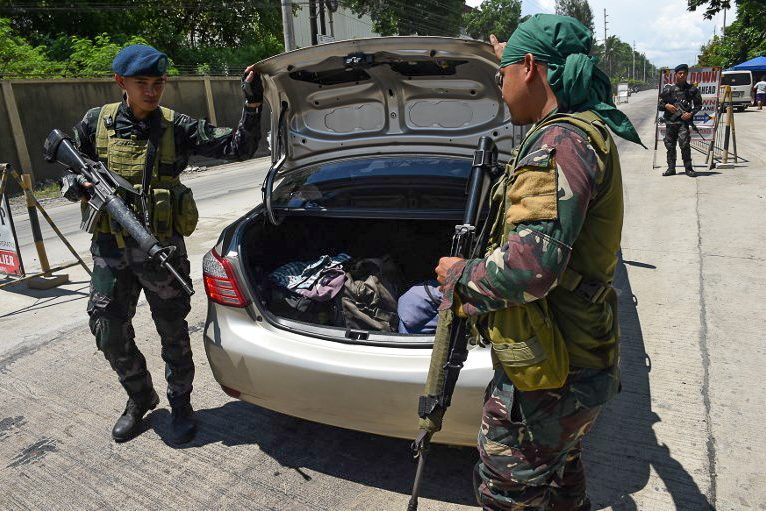 INSPECTION. Policemen check the trunk of a car at a checkpoint in Iligan City on May 24, 2017. Photo by Ted Aljibe/AFP 