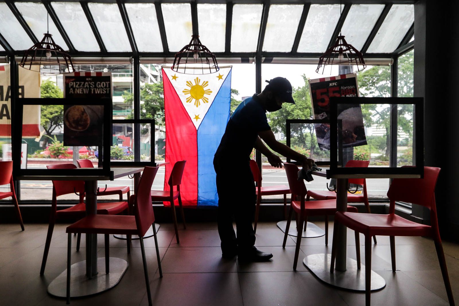 ECONOMY. A restaurant employee sets up acrylic dividers on tables for dine-in customers. Photo by KD Madrilejos/Rappler 