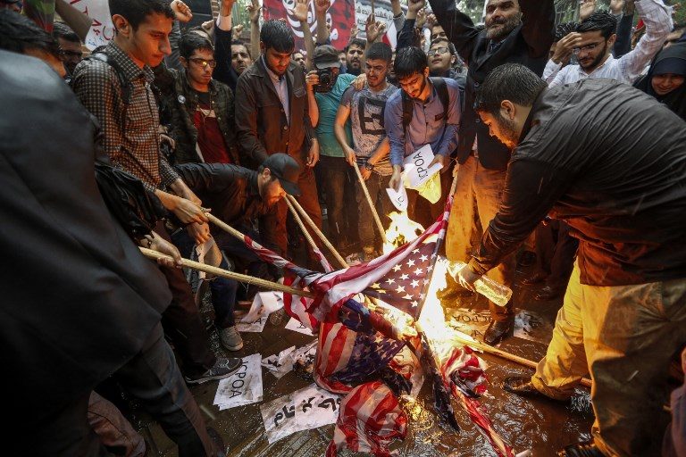 NUCLEAR DEAL. Iranians pour fuel on US flags set aflame during an anti-US demonstration outside the former US embassy headquarters in the capital Tehran on May 9, 2018, after US President Donald Trump's withdrawal from the 2015 nuclear deal. Photo by Atta Kenare/AFP   