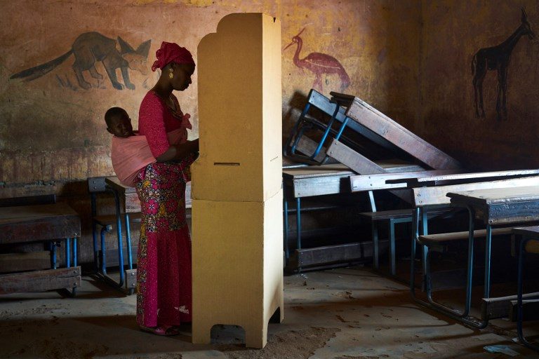 MALI VOTES. A woman with her child gets ready to cast her ballot at a polling station in Bamako on August 12, 2018 during the second round of Mali's presidential elections. Photo by Michele Cattani/AFP  