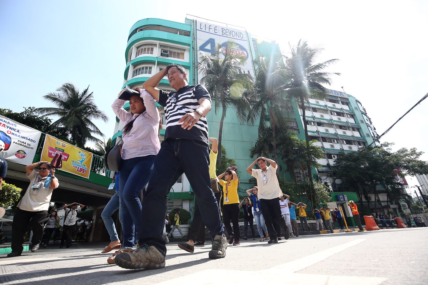 STAFF. MMDA employees cover their heads as they go out of the office. Photo by Ben Nabong/Rappler 