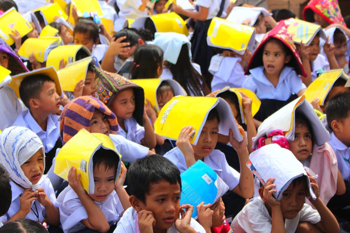 COVER. Students cover their heads with notebooks during the earthquake drill. Photo by Darren Langit/Rappler   