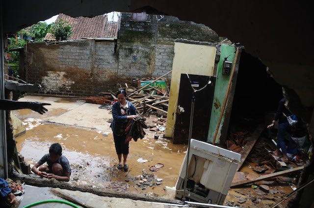 Warga membersihkan sejumlah barang barang di rumah yang rusak akibat banjir bandang di Bandung, Jawa Barat, pada 10 Februari 2016. Foto oleh Novrian Arbi/Antara 