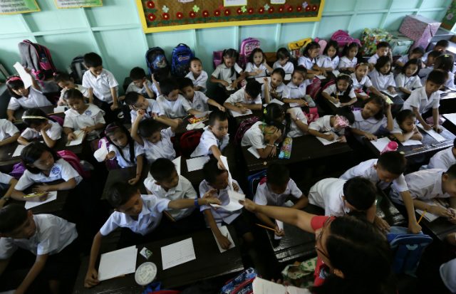 Elementary students get handed their papers in an overloaded classroom during the first day of school at the President Corazon Aquino Elementary School in Quezon city, east suburban Manila, Philippines, 02 June 2014. Photo by Dennis Sabangan/EPA  