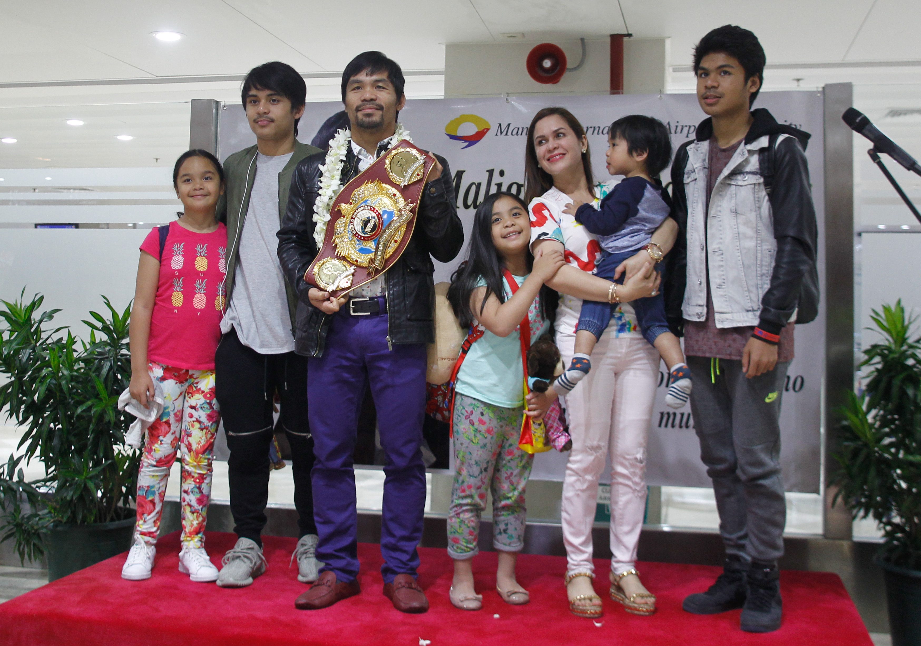 Filipino boxing icon Manny 'Pacman' Pacquiao (3-L) holding his World Boxing Organization WBO International Welterweight Championship title poses for pictures upon his arrival at the Ninoy Aquino International Airport in Manila, Philippines, 14 April 2016. Philippine boxer Manny Pacquiao arrived in Manila after his unanimous win over US boxer Timothy Bradley in Las Vegas, USA in their World Boxing Organization WBO International Welterweight Championship title bout. Pacquiao declared his retirement from boxing following his match to focus on his family and political career. Pacquiao is running for Senator in the upcoming Philippine elections on 09 May. EPA/MARK R. CRISTINO 