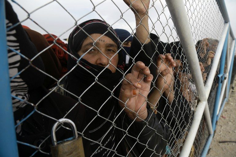 In this file photo, Iraqi refugees, who fled the Iraqi city of Mosul due to the fighting between government forces' and Islamic State (ISIS) group's jihadists, look from behind a fence at the UN-run al-Hol refugee camp in Syria's Hasakeh province, on December 5, 2016. Delil Souleiman/AFP 