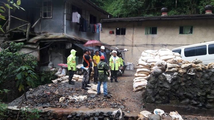 PREPARATION. The mining community in Barangay Ucab, Itogon found refuge in two concrete buildings at the foot of a mountain. Police are shown visiting them before the storm hit landfall. Sourced photos
  