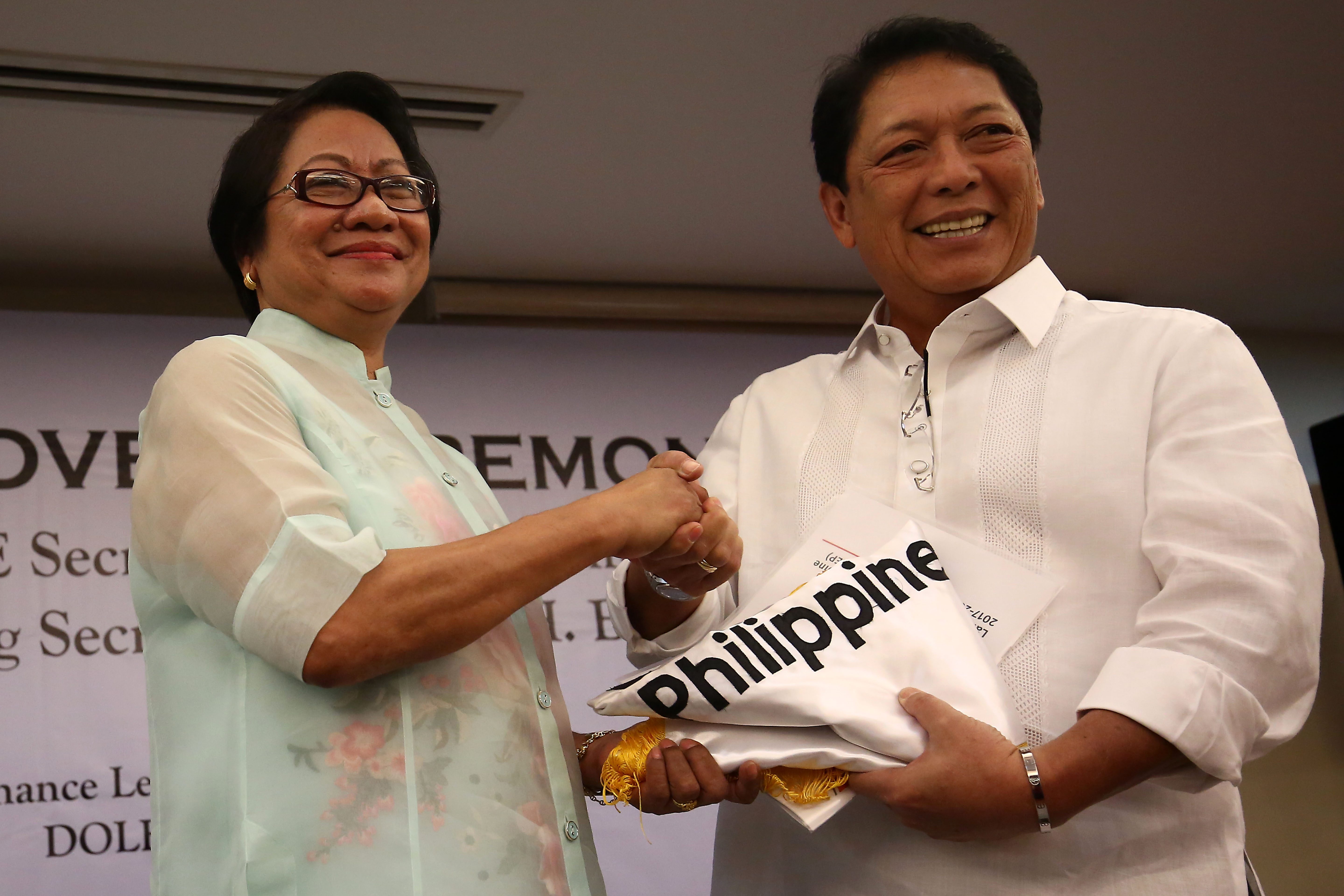 DOLE. Outgoing Secretary Rosalinda Baldoz hands over the agency flag to newly-installed Department of Labor and Employment (DOLE) Secretary Silvester Bello III during a short turnover ceremony at the DOLE main office in Intramuros. Photo by Ben Nabong/Rappler  