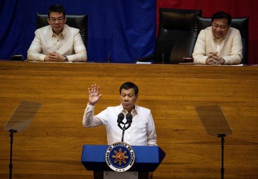 Philippine President Rodrigo Duterte gestures as he delivers his state of the nation address at Congress in Manila on July 24, 2017, as Senate President Aquilino Pimentel (L) and House Speaker Pantaleon Alverez (R) listen.
Philippine President Rodrigo Duterte vowed July 24 to press on with his controversial drug war that has claimed thousands of lives, as he outlined his vision of an "eye-for-an-eye" justice system. / AFP PHOTO / NOEL CELIS 