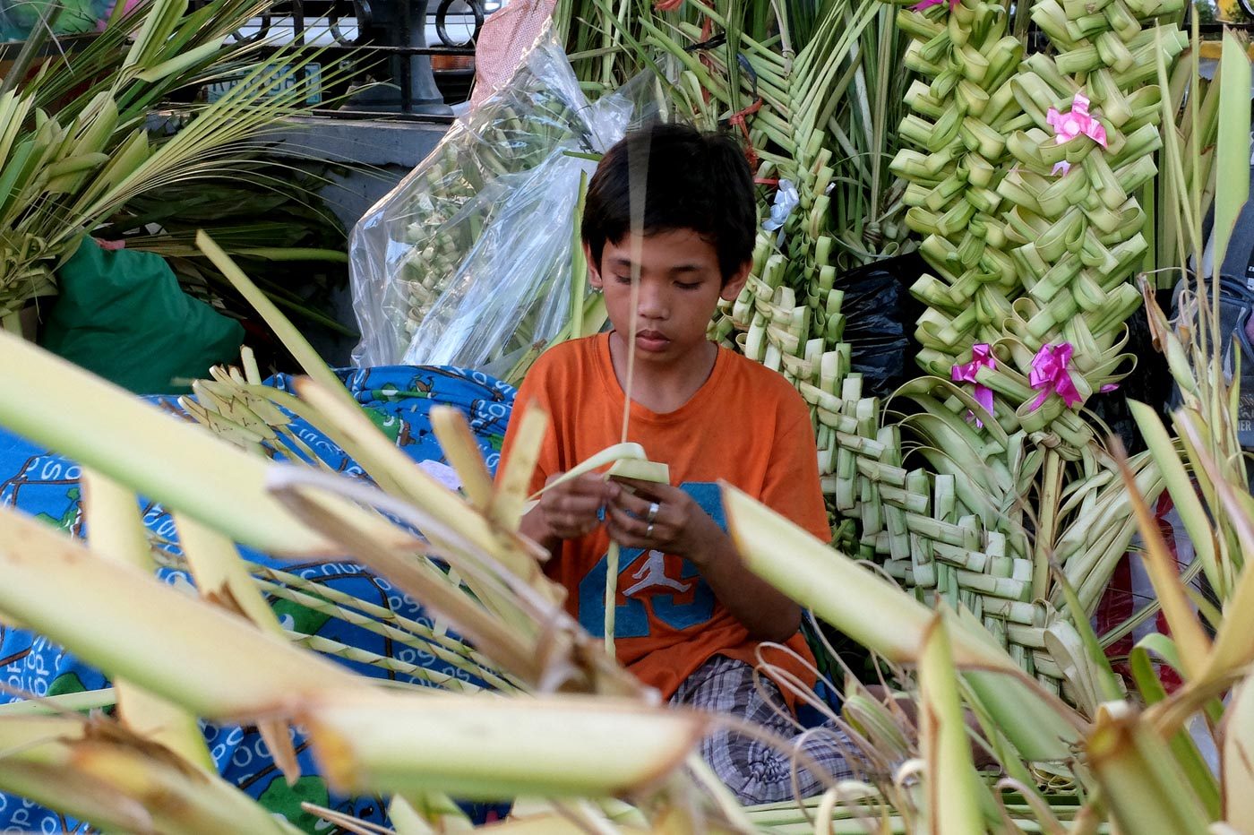 STARTING YOUNG. A boy makes a palaspas in front of the Sto Domingo church in Quezon City. Photo by Angie de Silva/Rappler   