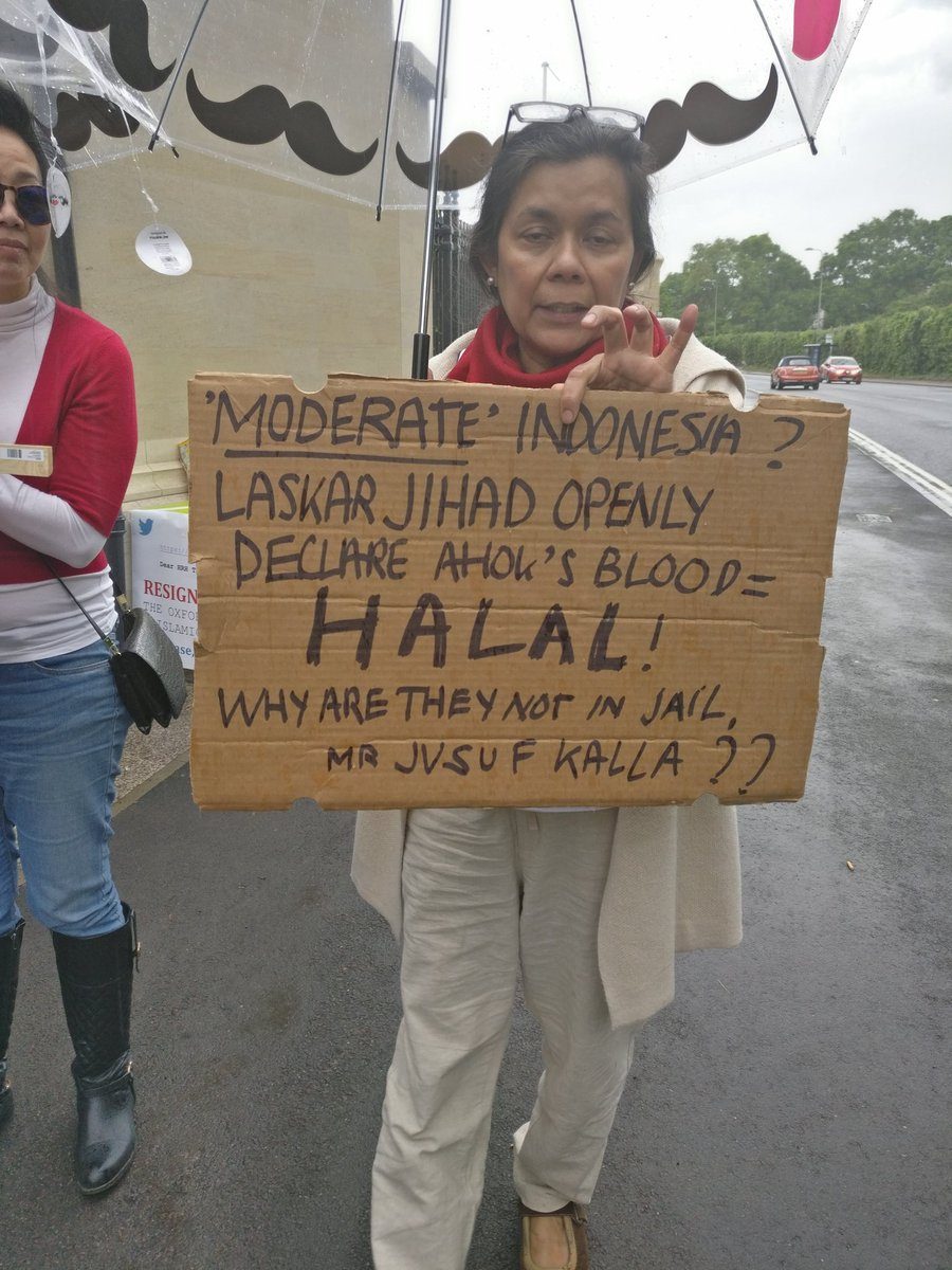 PROTES. Mariella Djorghi membawa poster yang memprotes kedatangan Wapres Jusuf "JK" Kalla untuk berpidato di Universitas Oxford pada Kamis, 18 Mei. Foto diambil dari akun @indaimanda  