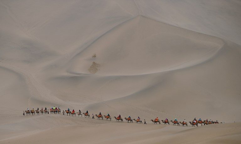 SILK ROAD. People ride camels in the desert in Dunhuang, China, on July 18, 2017 as stage 10 of The Silkway Rally continues. Photo by Franck Fife/AFP   
