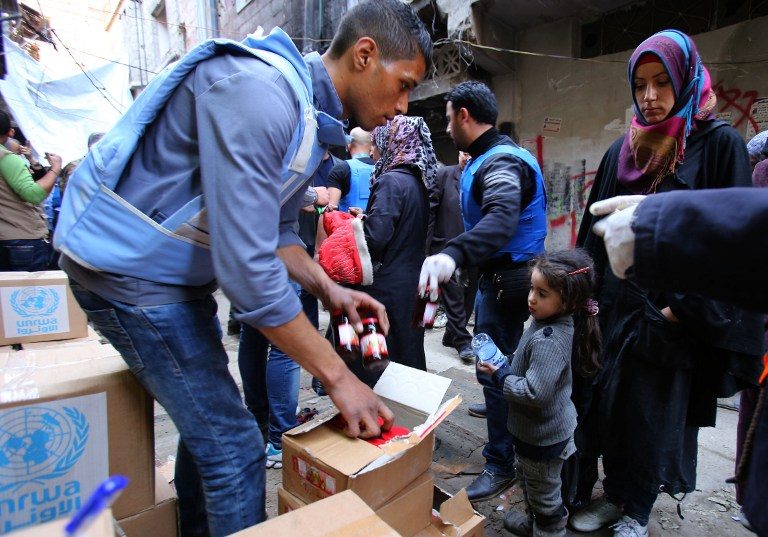Palestinian refugees receive aid items distributed by the United Nations Relief and Works Agency for Palestine Refugees (UNRWA) at the Yarmouk refuge camp, south of Damascus, on March 10, 2015. Youssef Karwashan/AFP 