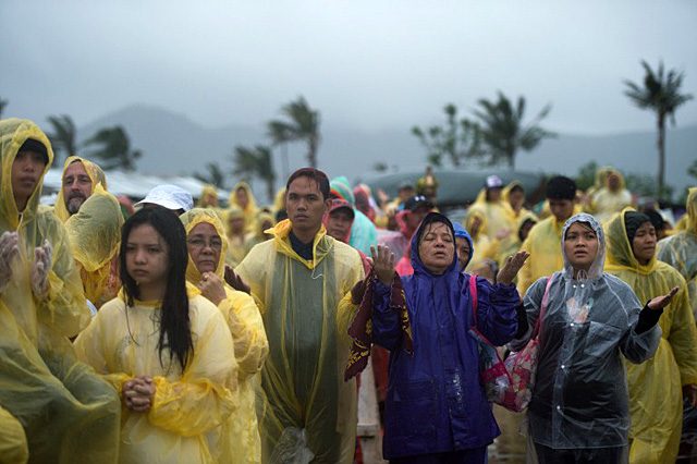 Devotees pray during a mass, held by Pope Francis (not seen) in Tacloban on January 17, 2015. Photo by Johannes Eiselle/AFP