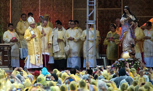 Pope Francis in raincoat holds a mass in Tacloban on January 17, 2015. Photo by Johannes Eiselle/AFP