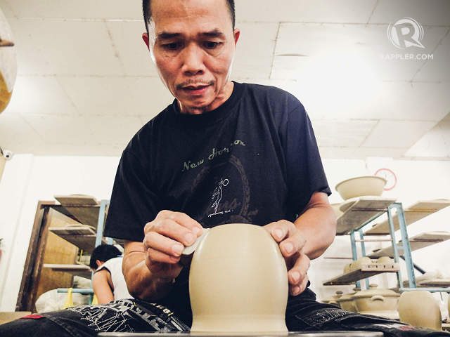 A potter's hand molds a piece of clay on top of a potter's wheel into a cup. Photo by  Bobby Lagsa/Rappler
  