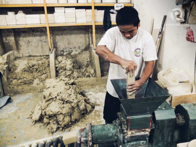A general worker pounds clay into a machine that will squeeze out air pockets inside the clay. Photo by Bobby Lagsa/Rappler
  