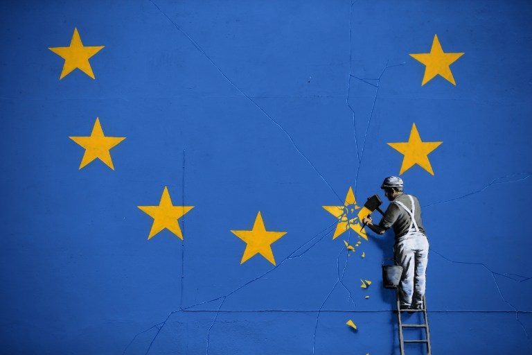 STREET ART. A painted mural by British graffiti artist Banksy depicting a workman chipping away at one of the stars on a European Union-themed flag is photographed in Dover, England on May 8, 2017. Photo by Daniel Leal-Olivas/AFP   