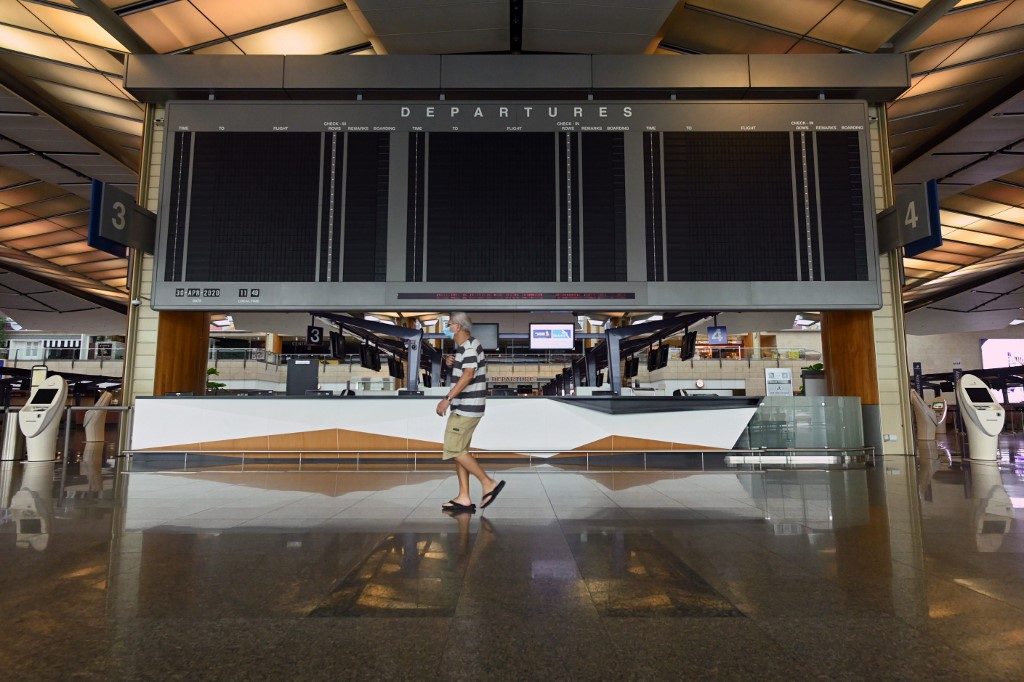 AVIATION SECTOR. A man wearing a face mask walks past a blank screen on April 30, 2020, at the departure hall at Singapore Changi Airport's terminal 2, which is set to suspend operations for 18 months from May 1, 2020, as the COVID-19 pandemic impacts the aviation sector, in Singapore. Photo by Roslan Rahman/AFP  