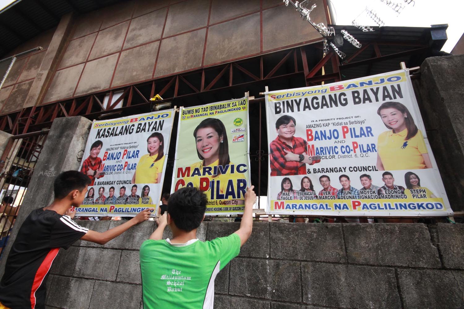 ALL SET. Supporters hang streamers of their candidates at the common poster area at the  Barangay Pasong Tamo covered court in Quezon City during the start of the campaign period for local elective posts. Photo by Joel Liporada/Rappler  