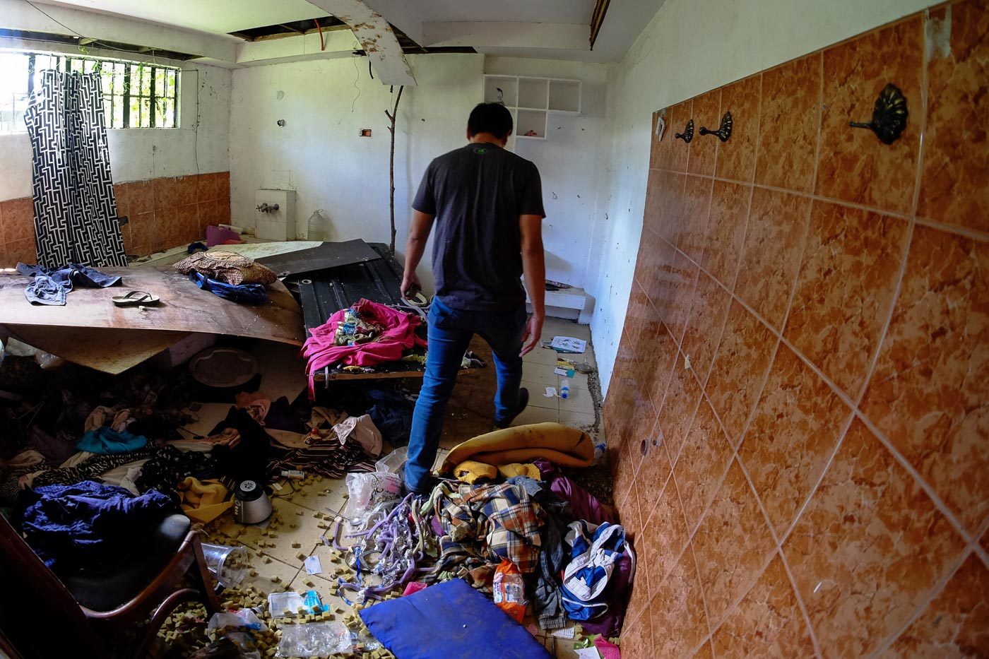 HIDEOUT. Timo Alonto Tamano shifts through debris inside a restroom of their house at the ground floor where Christians hid for safety during the siege. 