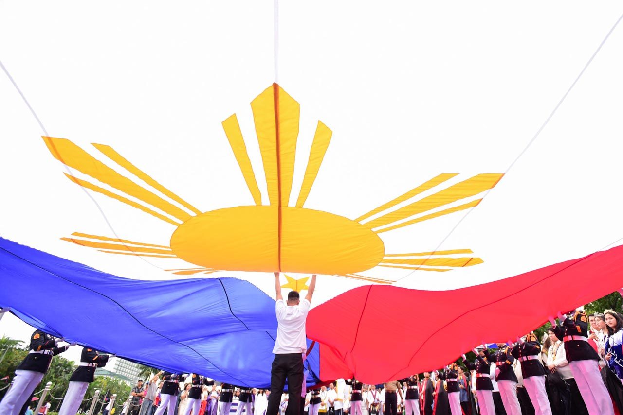 THE FLAG. A man helps hold up the Philippine flag for the 120th Independence Day rites in Luneta Park on June 12, 2018. Photo by Maria Tan/Rappler  