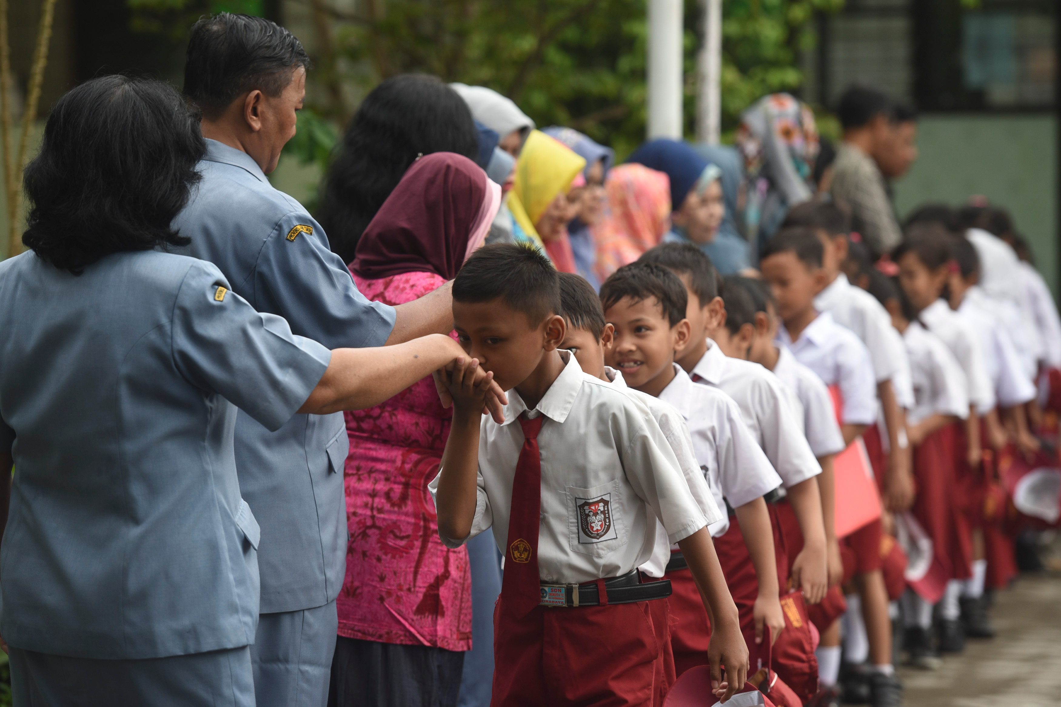 SALAMAN. Murid SD mengantre bersalaman dengan gurunya saat hari pertama masuk sekolah di SDN Simomulyo V, Surabaya, Jawa Timur, Senin, 18 Juli. Foto oleh Zabur Karuru/ANTARA 