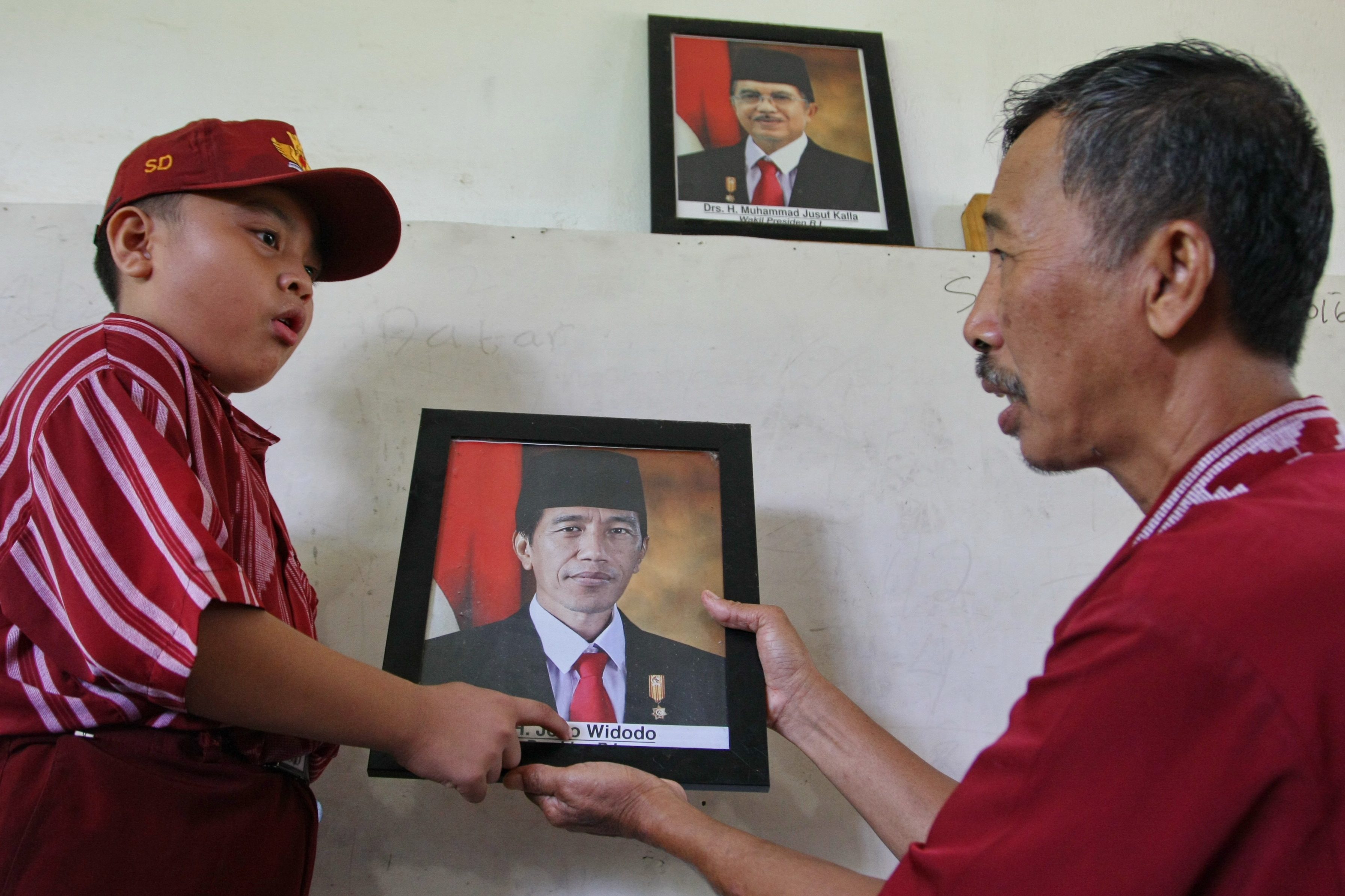 Guru memperlihatkan foto Presiden Jokowi kepada murid kelas I pada hari pertama masuk sekolah di SD 02 Kota Bangun, Konawe Selatan, Sulawesi Tenggara, pada 14 Juli 2016. Foto oleh Jojon/Antara   