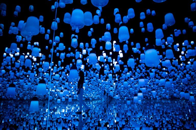 DIGITAL WATERFALL. A photo taken on May 1, 2018 shows a Japanese member of Teamlab collective walks and poses in a digital installation room with hanging lamps, that illuminate as the visitor nears and the light moving from one lamp to another around the room, at Mori Building Digital Art Museum in Tokyo. Photo by Behrouz Mehri/AFP  