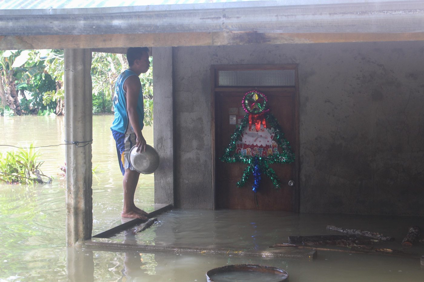 LIFE INTERRUPTED. A man armed with a basin checks his flooded home situated along the Loboc River. Photo by Michael Ortega Ligalig/Rappler 
