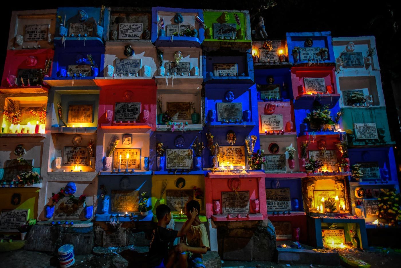 NIGHT FALLS. Candles lit freshly painted apartment tombs at the Barangka Cemetery in Marikina. Photo by Maria Tan/Rappler  