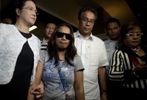 ILLEGAL RECRUITMENT CASE. In this photo taken on April 29, 2015, alleged recruiter Maria Cristina Sergio is escorted by Public Attorneys Office (PAO) chief Persida Acota and former Interior secretary Mar Roxas after Sergio turned herself in to authorities. Photo by Noel Celis/AFP   