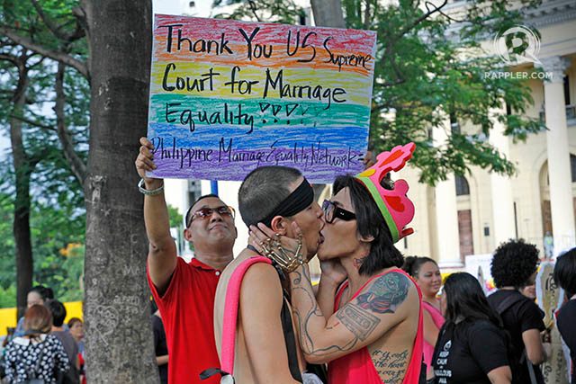 EQUALITY. A gay couple kisses while a man holds up a sign to celebrate a US Supreme Court ruling on marriage equality. Photo by Mark Z. Saludes/Rappler.com 