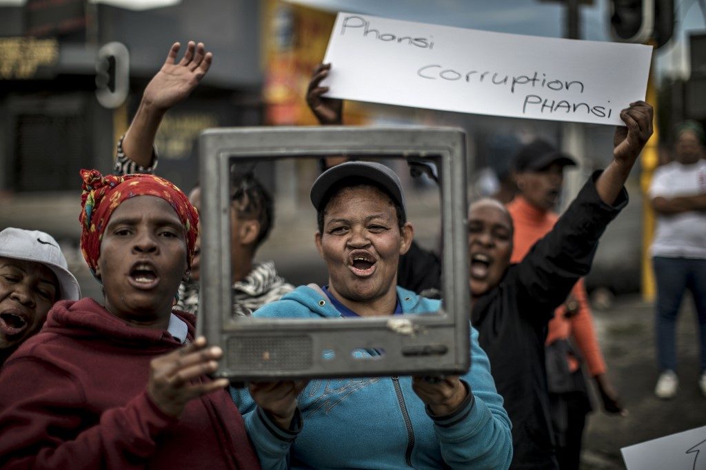 'DOWN WITH CORRUPTION.' A woman holds a banner reading Down with corruption' as they shout slogans and gesture, in Johannesburg, on April 23, 2019 during a protest against the lack of service delivery or basic necessities such as access to water and electricity, housing difficulties and lack of public road maintenance. File photo by Marco Longari/AFP  