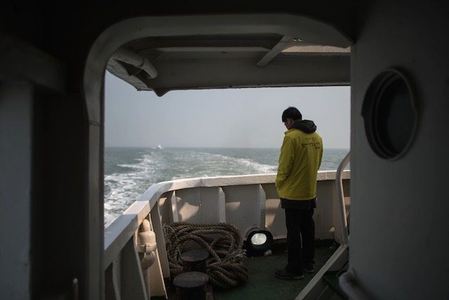 ONE YEAR LATER. A relative of a victim of the Sewol ferry disaster stands on the deck of a boat during a visit to the site of the sunken ferry off the coast of South Korea's southern island of Jindo, 15 April 2015. Ed Jones/Pool/EPA 