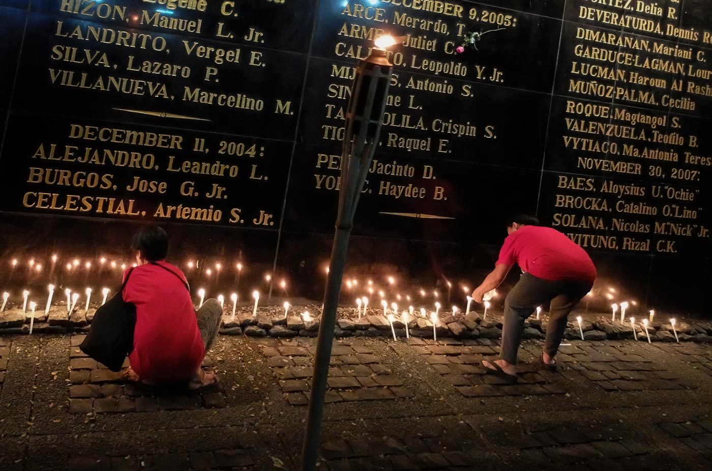 Relatives of victims of Martial Law light candles at the Bantayog ng mga Baynani wall of remembrance to honor the heroism of their fallen kin 
