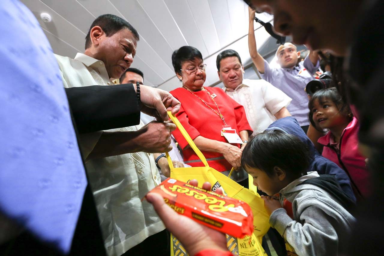 WITH THE PRESIDENT. DSWD Secretary Judy Taguiwalo beside President Rodrigo Duterte who is interacting with children of returning OFWs. Malacanang photo     