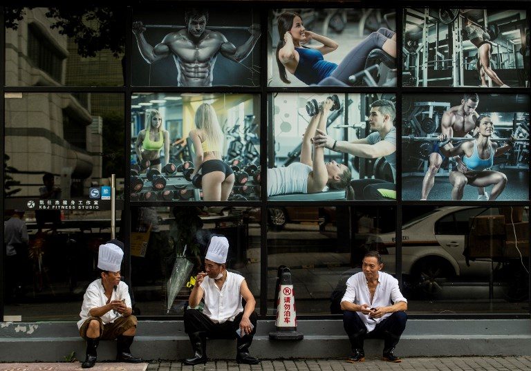 BREAKTIME. Three restaurant chefs take a break in front of a fitness studio in downtown Shanghai on September 4, 2018. Photo by Johannes Eisele/AFP  