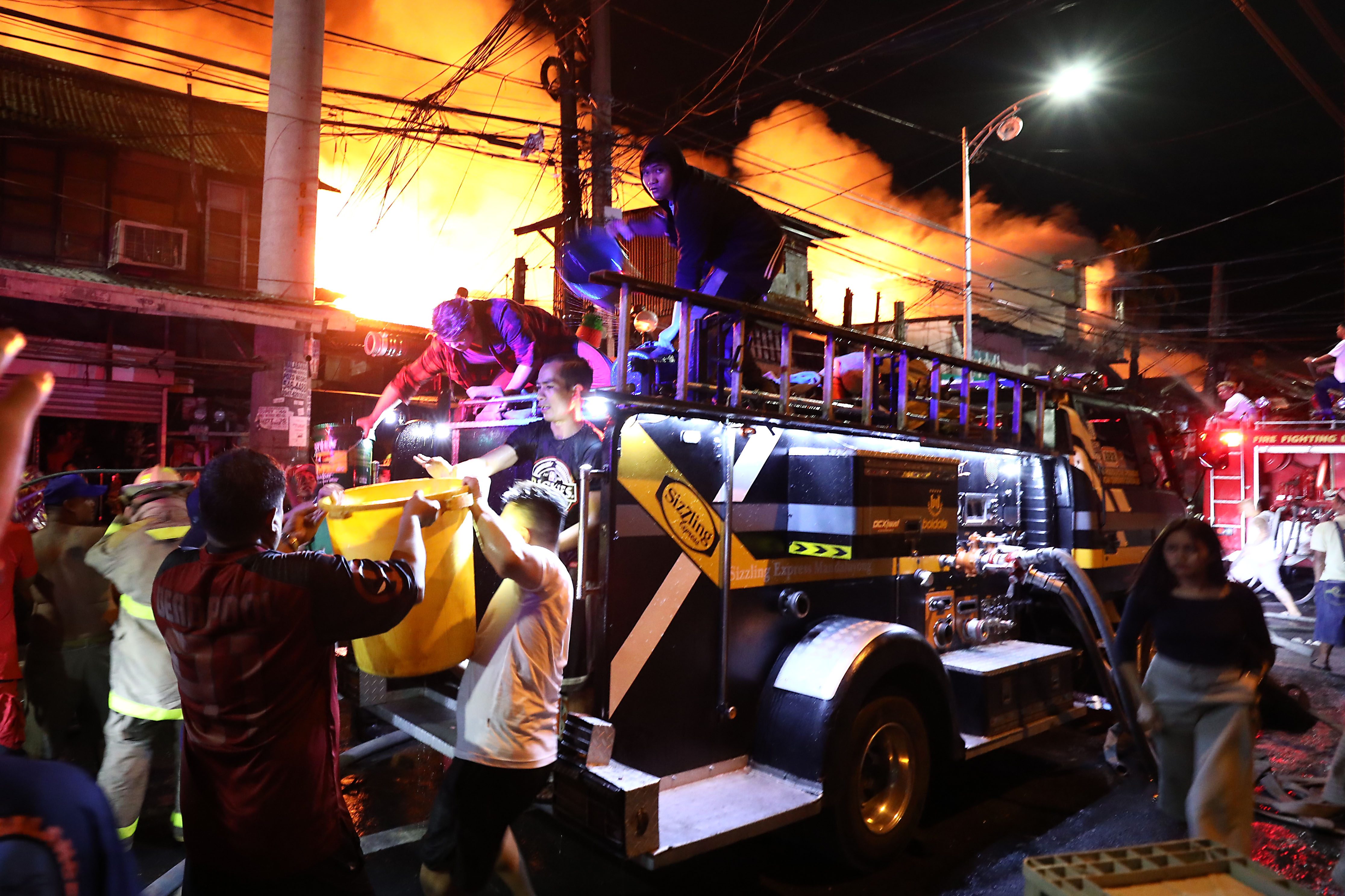 COMMUNITY EFFORT. Residents help firemen put out the fire in Sta Ana. Photo by Ben Nabong   
