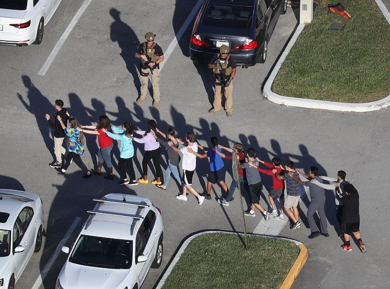FLORIDA SHOOTING. People are brought out of the Marjory Stoneman Douglas High School after a shooting at the school that killed and injured multiple people on February 14, 2018, in Parkland, Florida. Photo by Joe Raedle/Getty Images/AFP   
