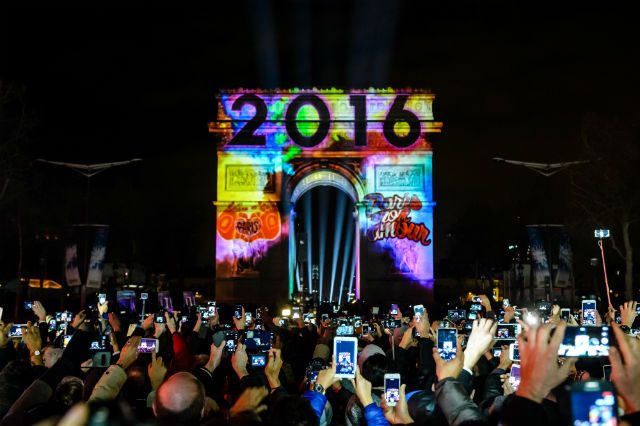 People gather on the Champs Elysees to watch the New Year video display on the Arc de Triomphe in Paris, France, January 1, 2016. Photo by Christophe Petit Tesson/EPA 