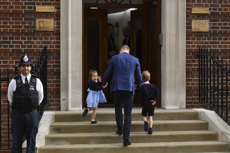 VISIT. Princess Charlotte of Cambridge (L) turns to wave at the media as she is lead in with her brother Prince George of Cambridge (R) by their father Britain's Prince William, Duke of Cambridge, (C) at the Lindo Wing of St Mary's Hospital in central London, on April 23, 2018, to visit Catherine, Duchess of Cambridge, and their new-born son. Photo by Ben Stansall/AFP 