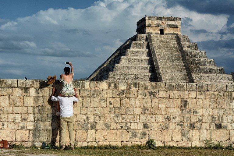 EQUINOX. A woman on a man's shoulders' takes a picture of the Kukulcan Pyramid at the Mayan archaeological site of Chichen Itza in Yucatan State, Mexico, during the celebration of the spring equinox on March 21, 2018. Photo by Luis Perez/AFP  