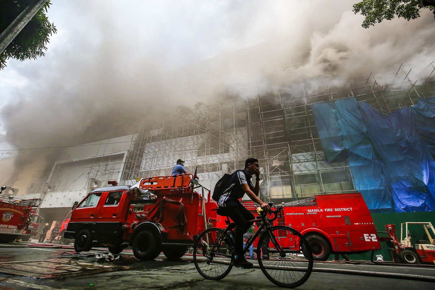 DEADLY SMOKE. A man cycles past the Waterfront Manila Pavilion Hotel & Casino after a fire broke out at the casino complex on March 18, 2018. Photo by Ben Nabong/Rappler 