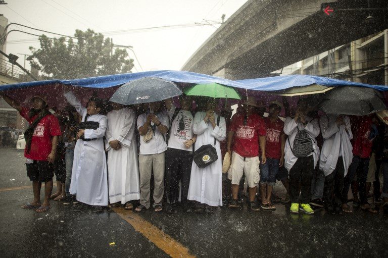 DESPITE RAIN. Protesters take shelter from the rain during a protest to commemorate the 46th anniversary of the declaration of Martial Law by the late dictator Ferdinand Marcos in Manila on September 21, 2018. Photo by Noel Celis/AFP   