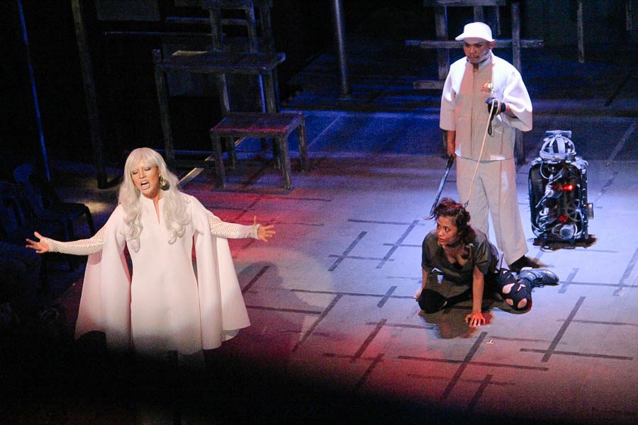 Grand Vidame Inky (Carla Guevara-Laforteza) sings, as Protektanod Bogs detains Nazty (Anna Luna). 